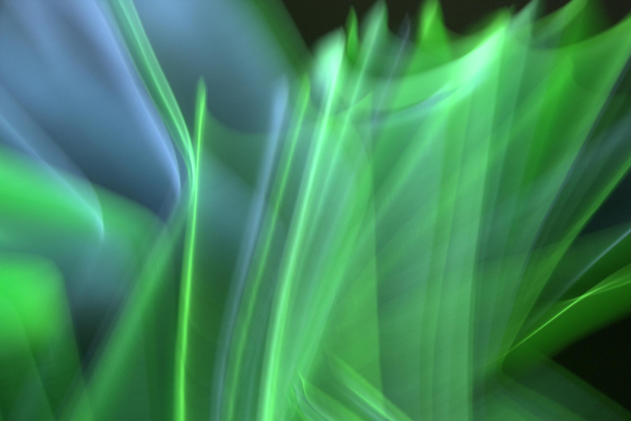 Dynamic abstract photo capturing vibrant green and blue light waves in motion.